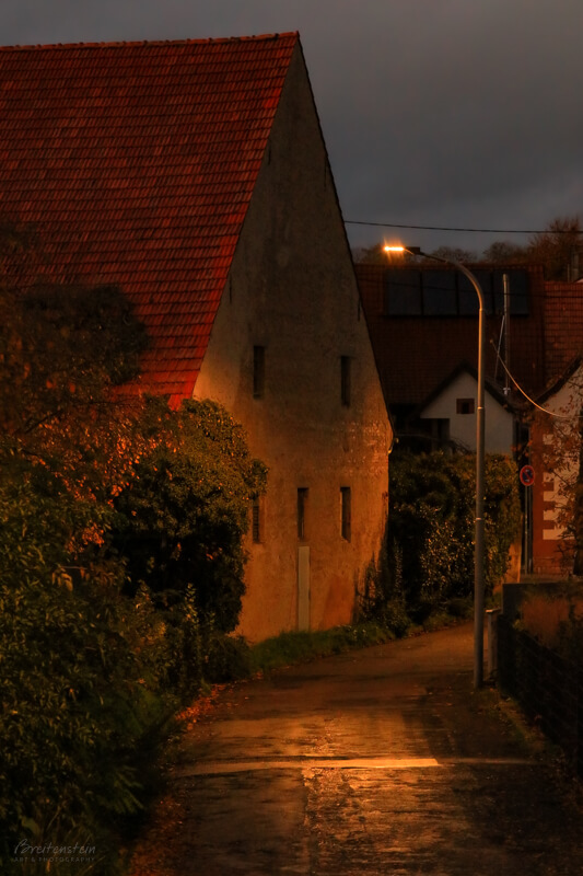 red-roof-stone-barn-street-lamp-website-800 Photo in warm colors of a large, old, red tile roofed stone barn, illuminated by a street lamp.