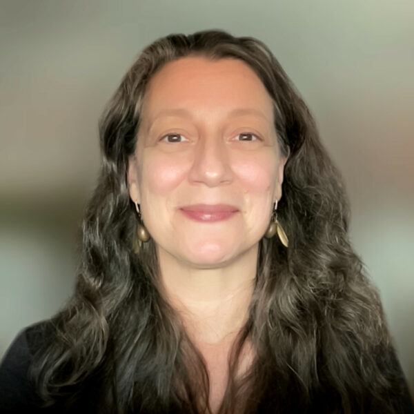 Head shot of Marlene Breitenstein, smiling, with long hair and a blurry background.